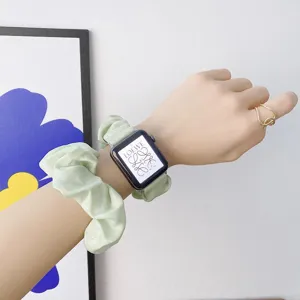 Detailaufnahme eines weichen grünen Scrunchie-Uhrenarmbands am Handgelenk, elastisch.