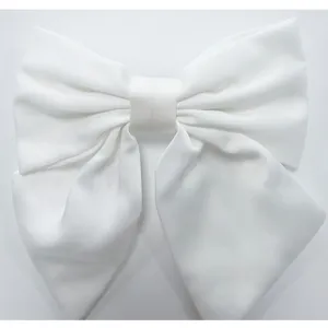 Gros plan détaillé d'un grand nœud pour cheveux en tissu blanc avec texture satinée douce.