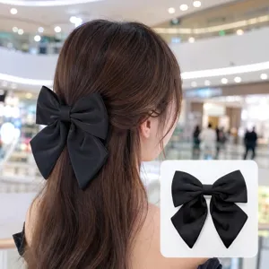 Détail pince à cheveux nœud satin noir, grand accessoire élégant pour coiffure.