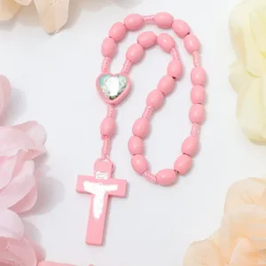 Pink wooden rosary bead bracelet detailed shot, featuring alloy cross and heart center.