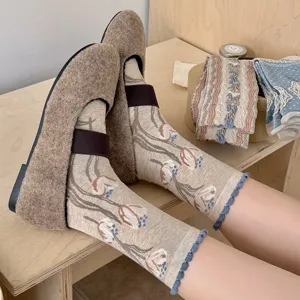Gros plan détaillé de chaussettes mi-mollet rétro à fleurs kaki avec bord roulé bleu.