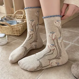Gros plan de chaussettes vintage à fleurs en kaki, dotées d'un joli bord roulé bleu douillet.