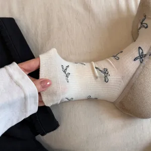 Detailaufnahme von Zehensocken mit niedlichem Schleifen-Print und kuscheliger Strickoptik.