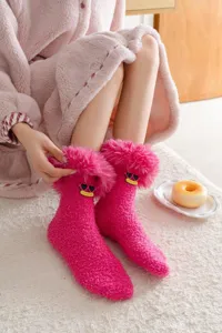 Détail gros plan de chaussettes peluche rose mignonnes avec broderie visage drôle de lunettes.