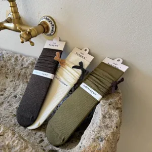 Dettaglio di calze a costine con fiocchi carini, presentate in tre bellissimi colori autunnali.