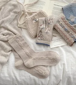 Vue detaillee de chaussettes florales retro et accessoires vintage sur tissu blanc.