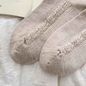 Gros plan de chaussettes en tricot kaki vintage avec texture florale délicate et coton doux.