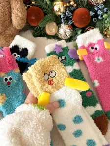 Close-up view of fluffy coral fleece winter socks with funny 3D cartoon embroidered faces.