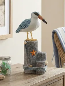 Coastal nautical seabird figurine on wooden piling with starfish and shells for home decor.