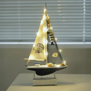 Wooden sailboat model nautical decor with LED lights and shells for home table display.