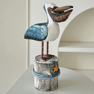 Figura de pelícano de madera tallada a mano sobre base de tronco con decoración marina.