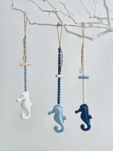 Detail view of wooden nautical seahorse hanging ornaments with bead strings, coastal decor.