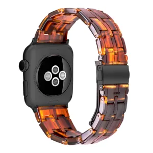 Detailed close-up view of amber resin watch strap links with black metal folding clasp.