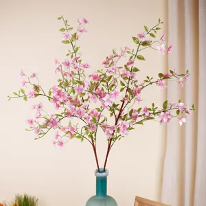 Kunstmatige roze bloemtakken in blauwe glazen vaas voor interieurdecoratie thuis