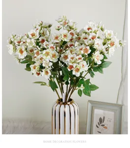 Vue détaillée d'un arrangement de roses blanches artificielles dans un vase blanc et or de luxe.