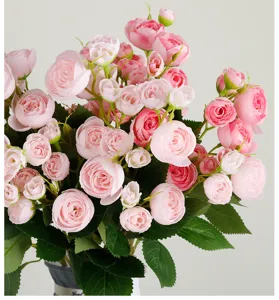 Detailed close-up of pink artificial tea rose bouquet, delicate flower buds with green leaves.