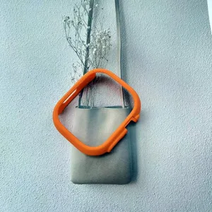 Detailed shot of bright orange protective smartwatch case hanging on a minimalist grey wall bag.