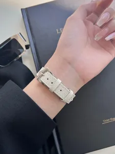 Dettaglio cinturino orologio in pelle bianca, fine trama incrociata con fibbia argento.