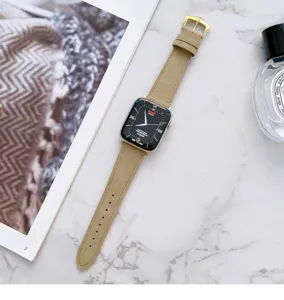 Primo piano dettaglio di un cinturino smartwatch in pelle beige vintage su marmo bianco.