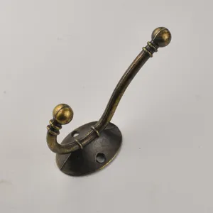 Close-up view of antique bronze metal coat hook with double prongs and wall mounting base.