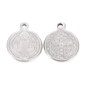 Close-up detail of stainless steel round religious pendant with embossed Saint Benedict motif.