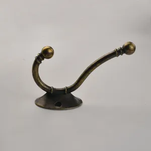 Detailed close-up of vintage bronze coat hook, antique metal wall mount hook for cabinet.