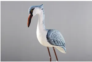 Coastal bird ornament close-up showing hand-painted blue and white wooden texture and slender legs.