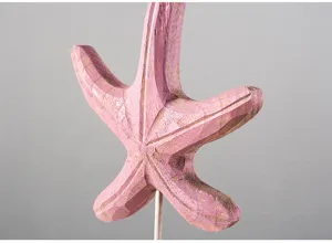 Detail view of pink carved wooden starfish home decor ornament displayed on metal stand.