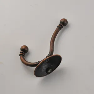 Detail view of a vintage bronze double coat hook, antique wall-mounted hardware hanger.