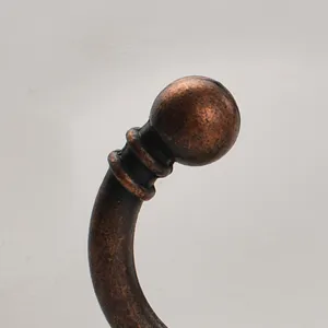 Close-up view of antique bronze cabinet hook, vintage curved wall coat hook detail.