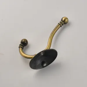 Detailed view of vintage antique bronze metal coat hook, wall mounted single hook hardware.