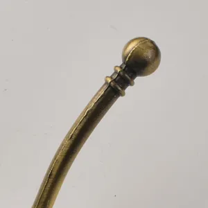 Antique brass coat hook detail, retro metal furniture hardware, single wall-mounted robe hook.