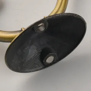 Detail view showing the sturdy mounting base and structure of a vintage black brass coat hook.