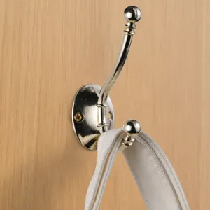 Close-up detail of a silver metal double coat hook mounted on wood panel showing hanging strap.