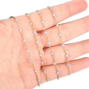 Close-up detail of stainless steel gold plated chain with light blue enamel beads for jewelry.