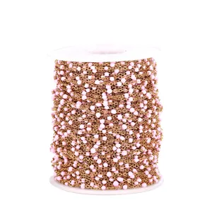 Close-up of pink enamel bead chain, golden DIY jewelry making chain detail view.