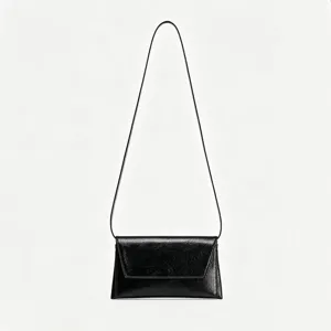 Vue rapprochée des détails du sac à bandoulière en cuir verni noir minimaliste et élégant.