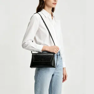Vue détaillée du sac porté travers en cuir noir présenté sur mannequin pour effet.