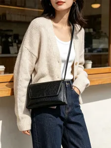 Vue détaillée d'un sac à bandoulière noir et minimaliste porté par le mannequin.