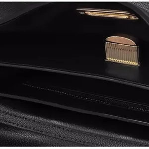 Détail intérieur de sac bandoulière en cuir noir avec serrure dorée et multiples compartiments.