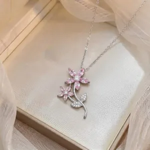 Detalle en primer plano del colgante de doble flor de circonita rosa y fina cadena de plata.