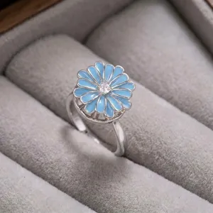 Exquisito anillo de flor de esmalte azul con circons brillante en tono plateado detalle.