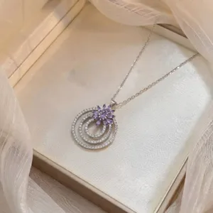 Primer plano del elegante collar de plata con colgante de flor de circonita morada.