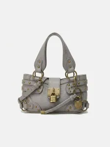 Sac bandoulière de moto vintage pour femme avec serrure métallique et détails de boucles.