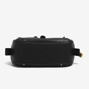 Bolso de hombro estilo moto en cuero negro con tachuelas y candado lateral elegante.