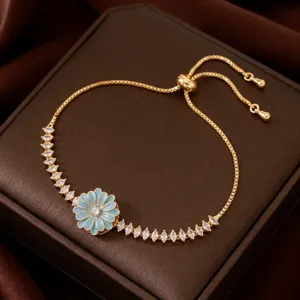 Elegante pulsera dorada con colgante de flor esmaltada en azul claro y cristales de circonita.