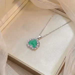 Vista de cerca del collar con colgante de piedra verde en forma de corazon con circonitas.