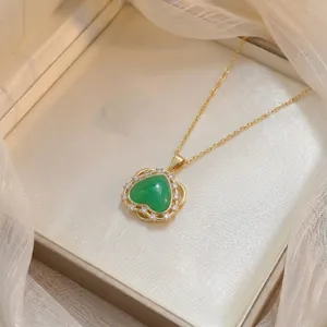 Vista detallada de un collar bañado en oro con colgante de corazón verde y circonitas brillantes.