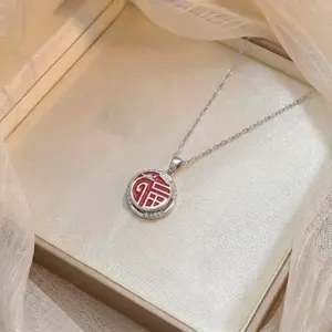 Detalle de un collar de plata con un colgante Fu de esmalte rojo y circonitas brillantes.