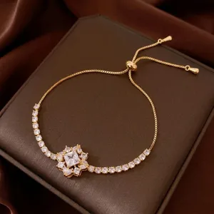 Primer plano detallado de pulsera deslizante de circonio dorado con dijes de cristal brillante.